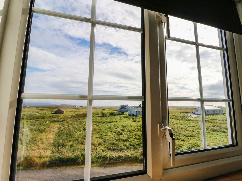 A view from a window showing houses and a field at Old School House in Isle Of South Uist
