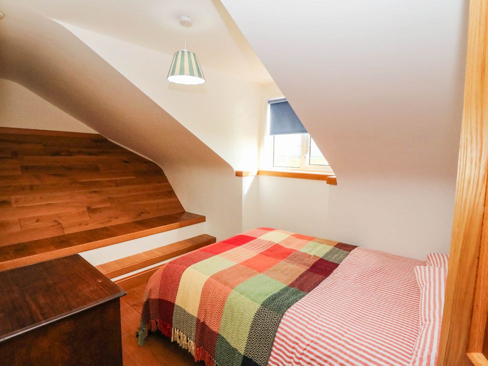 A bedroom with a bed and staircase at Old School House Isle Of South Uist
