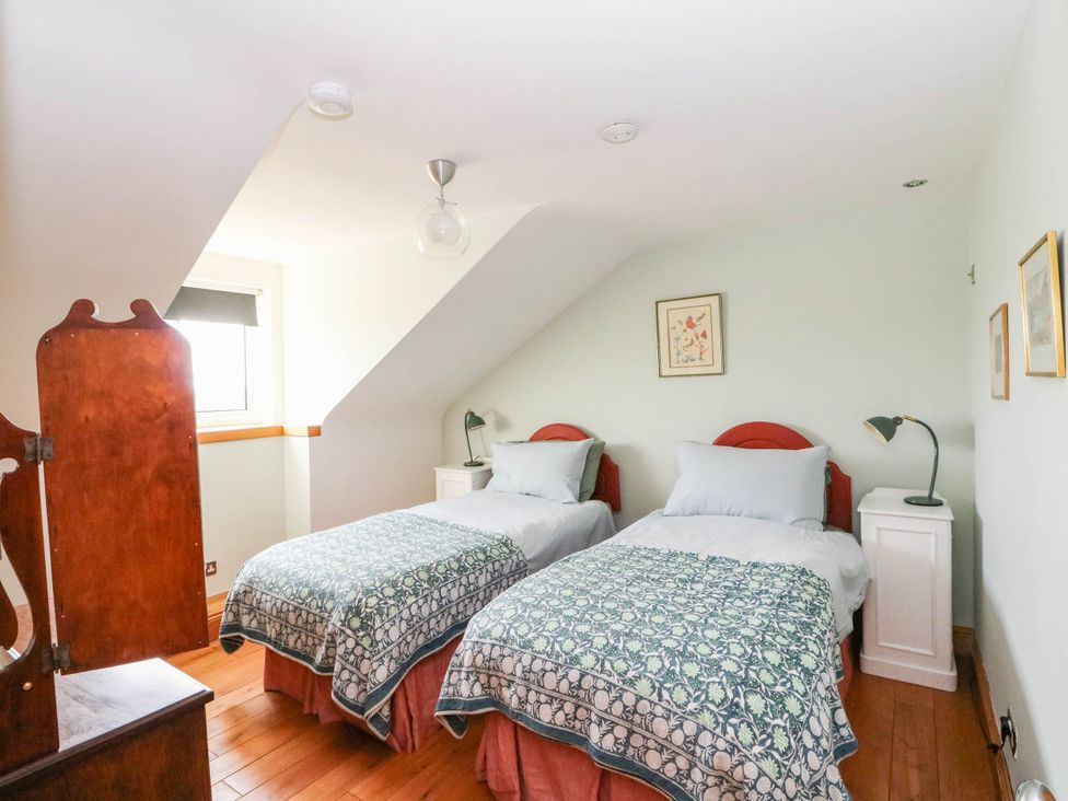 A bedroom with two beds and a nightstand at Old School House in Isle Of South Uist