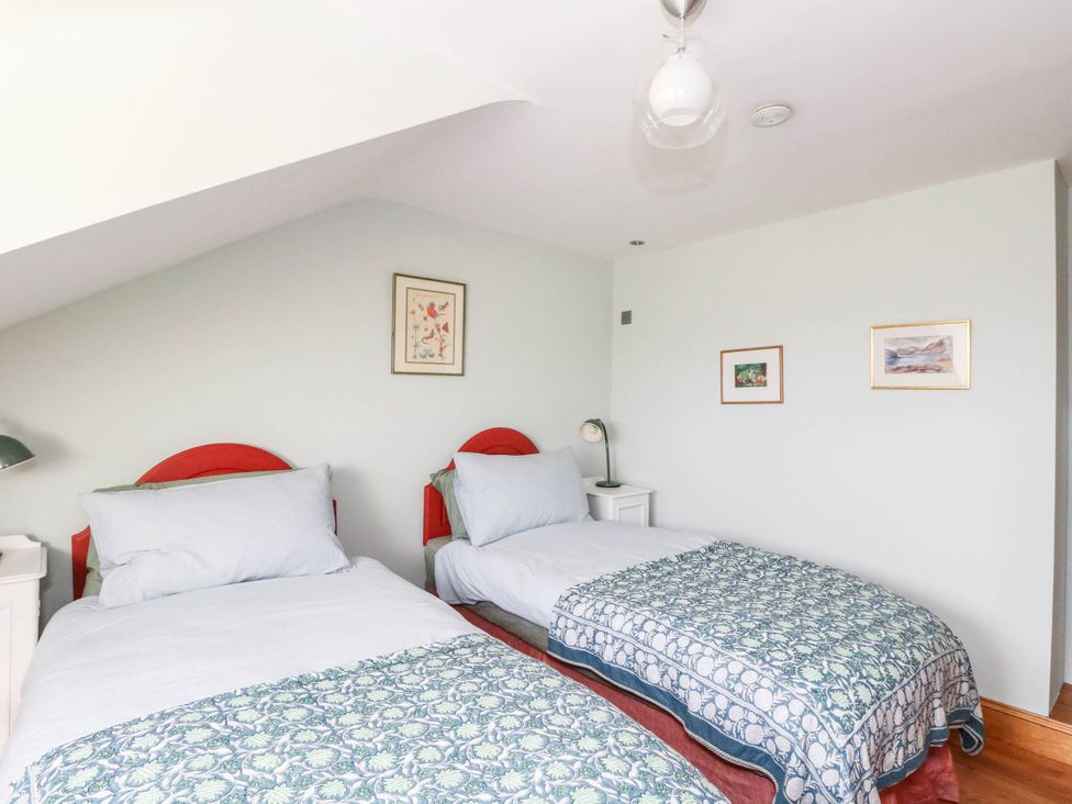 A bedroom with two beds and artwork on the wall at Old School House in Isle Of South Uist