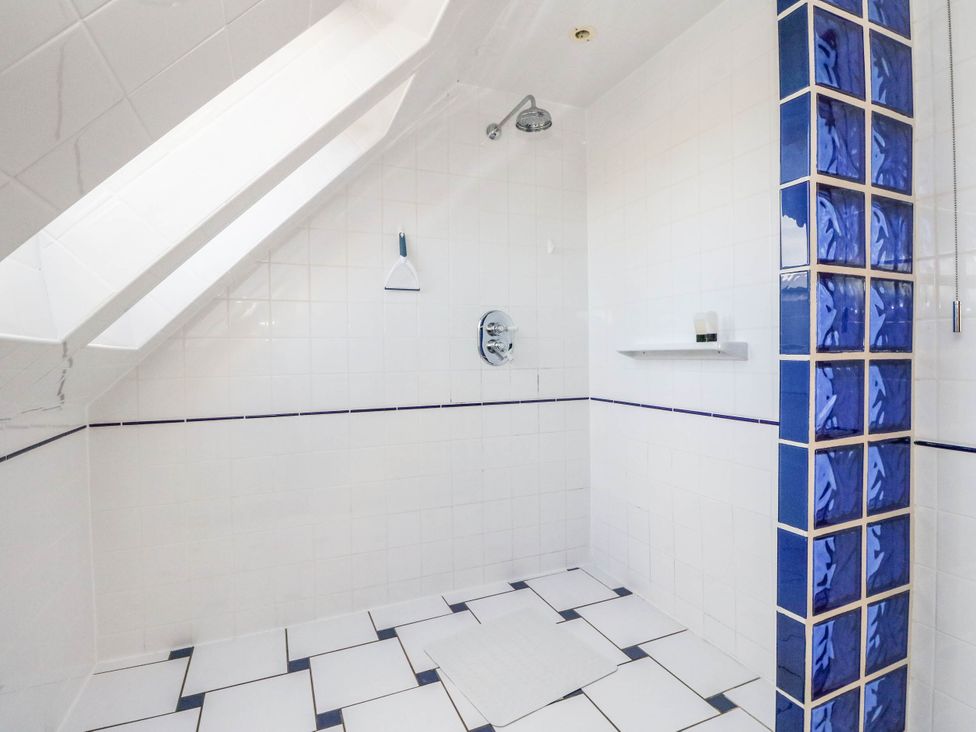 A bathroom with a shower and tiled walls at Old School House in Isle Of South Uist