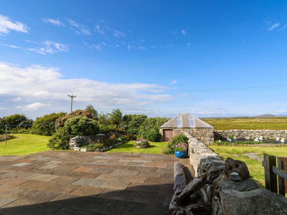 A garden with a stone wall and shed at The Old School House in Isle Of South Uist