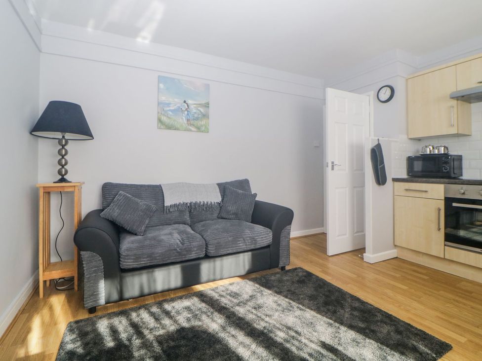 A living room with a sofa and kitchen unit at Devon Seaside Apartment in Paignton