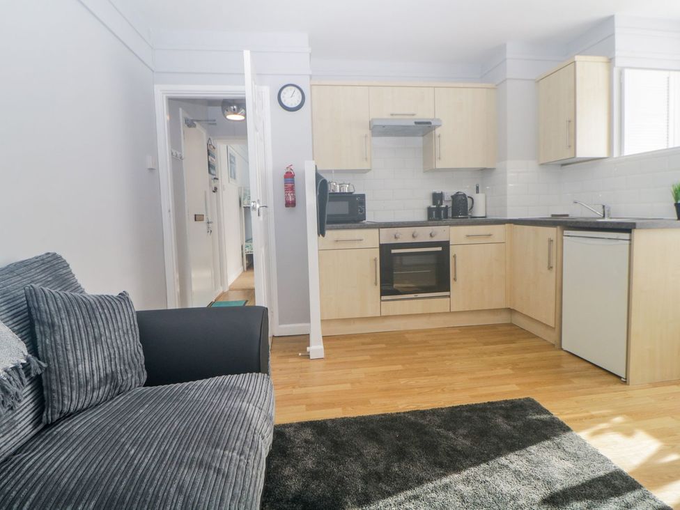A kitchen with cabinets and a sofa at Devon Seaside Apartment in Paignton