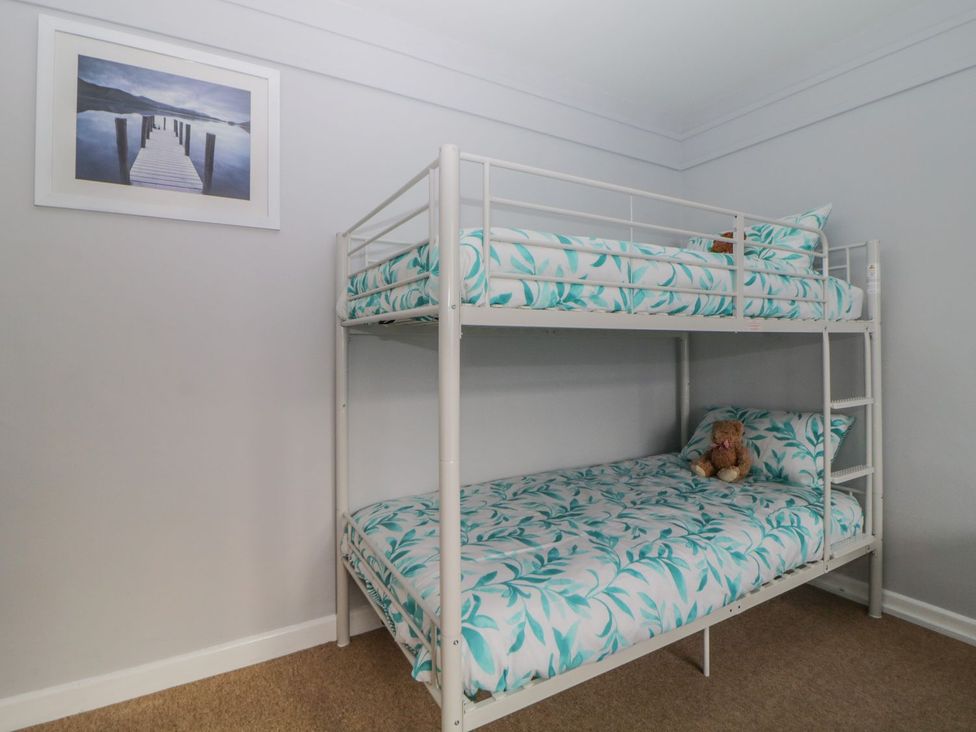A bunk bed with striped bed linens and a framed picture at Devon Seaside Apartment in Paignton