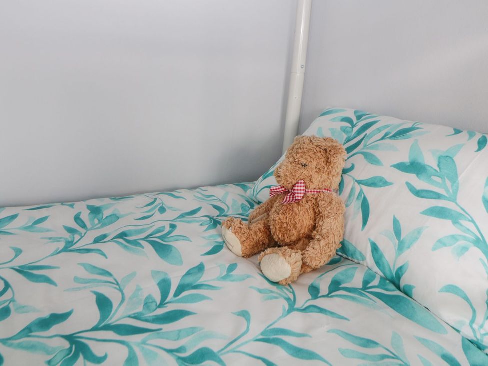 A bed with a teddy bear on the pillow in Devon Seaside Apartment Paignton