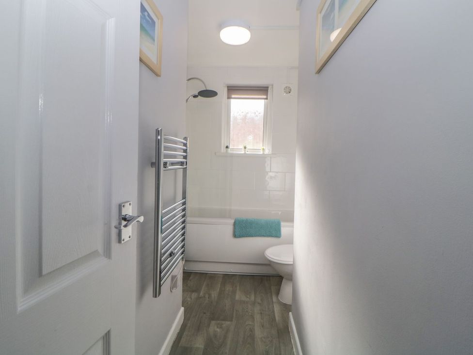 A bathroom with a bathtub and towel rail at Devon Seaside Apartment in Paignton