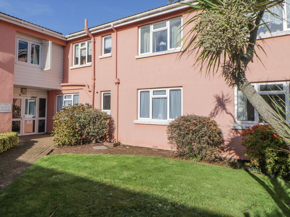 An outdoor area with a pink building and shrubs at Devon Seaside Apartment Paignton