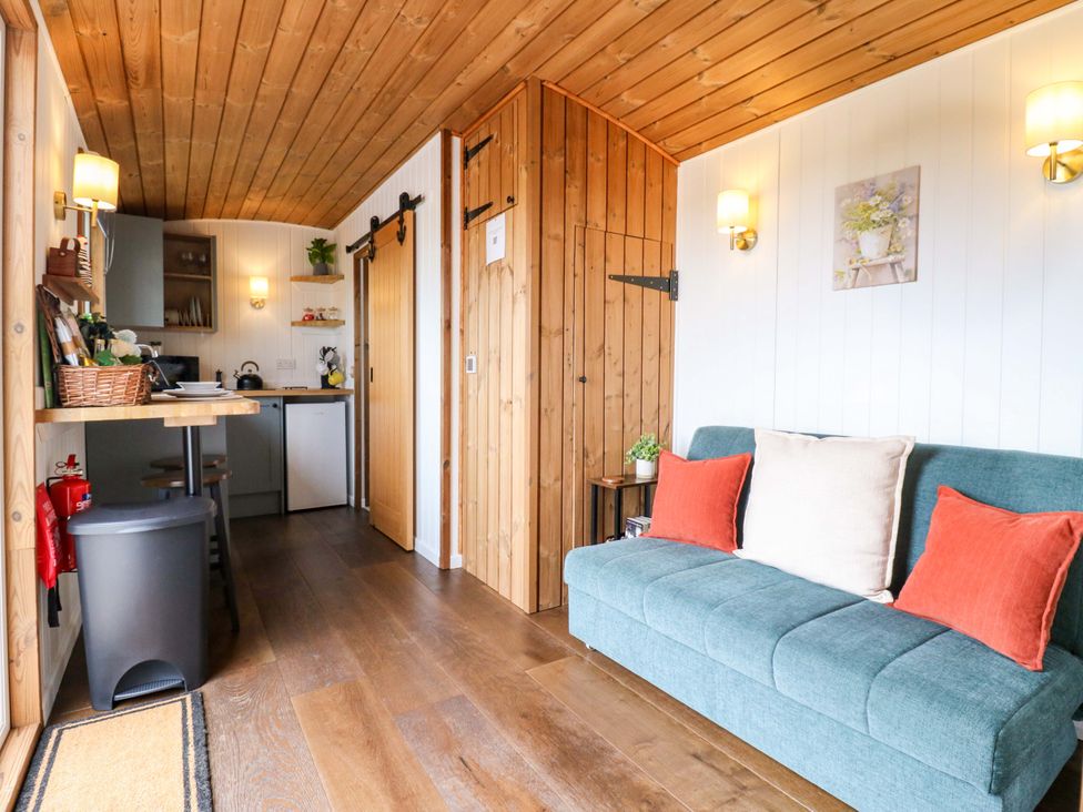 A living room with a sofa and kitchenette at The Kestrel in Cambridge