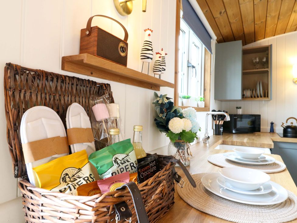 A kitchen with a basket filled with snacks and slippers at The kestrel in Cambridge