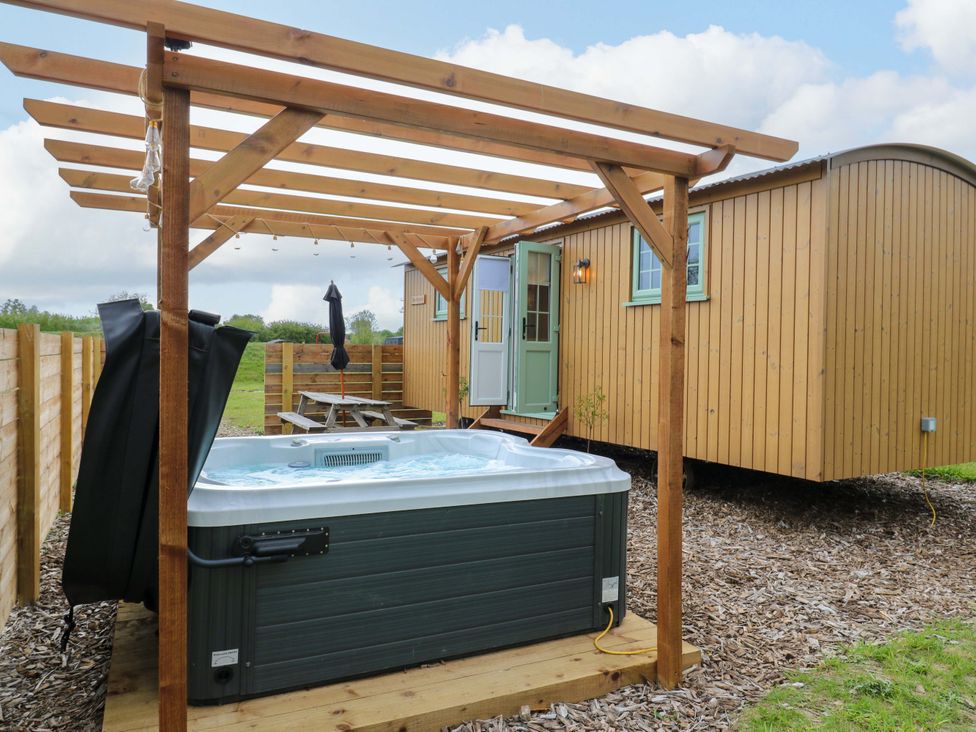 A hot tub beside a wooden cabin with seating at The Kestrel in Cambridge