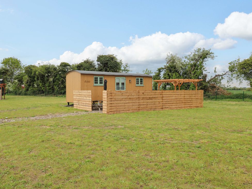 A wooden cabin with a fenced area and outdoor seating at The kestrel in Cambridge