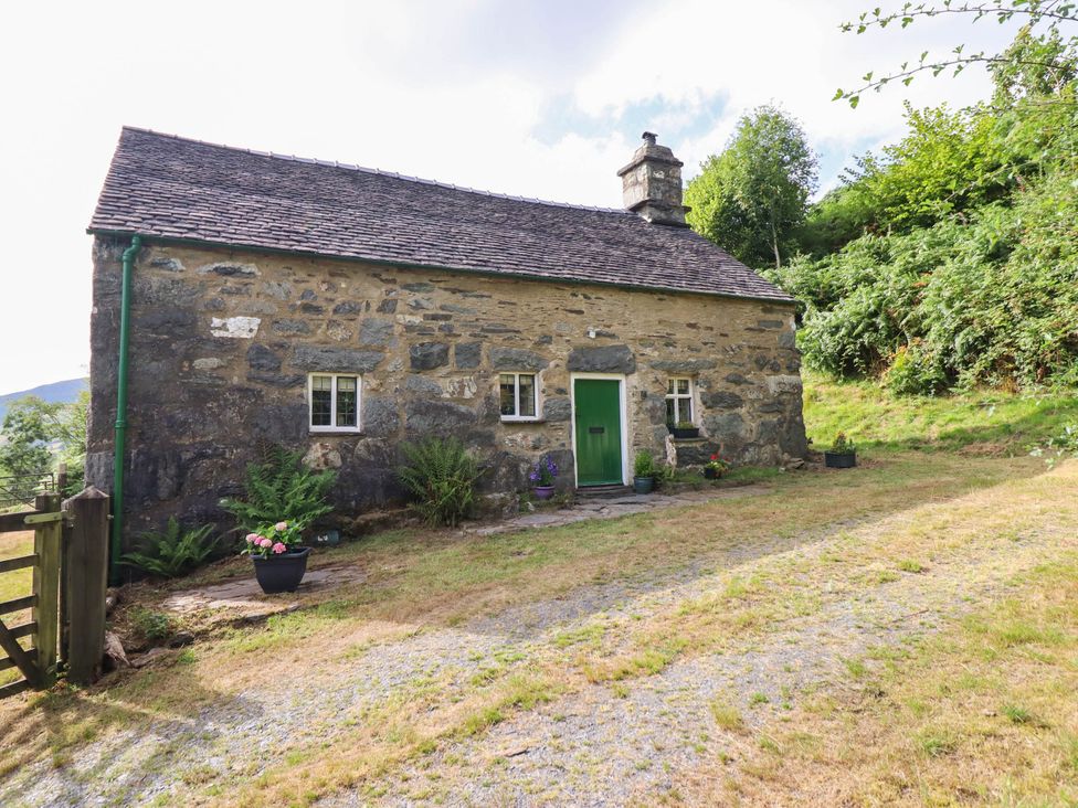 A cottage with a green door and garden plants at Frondirion in Dinas Mawddwy