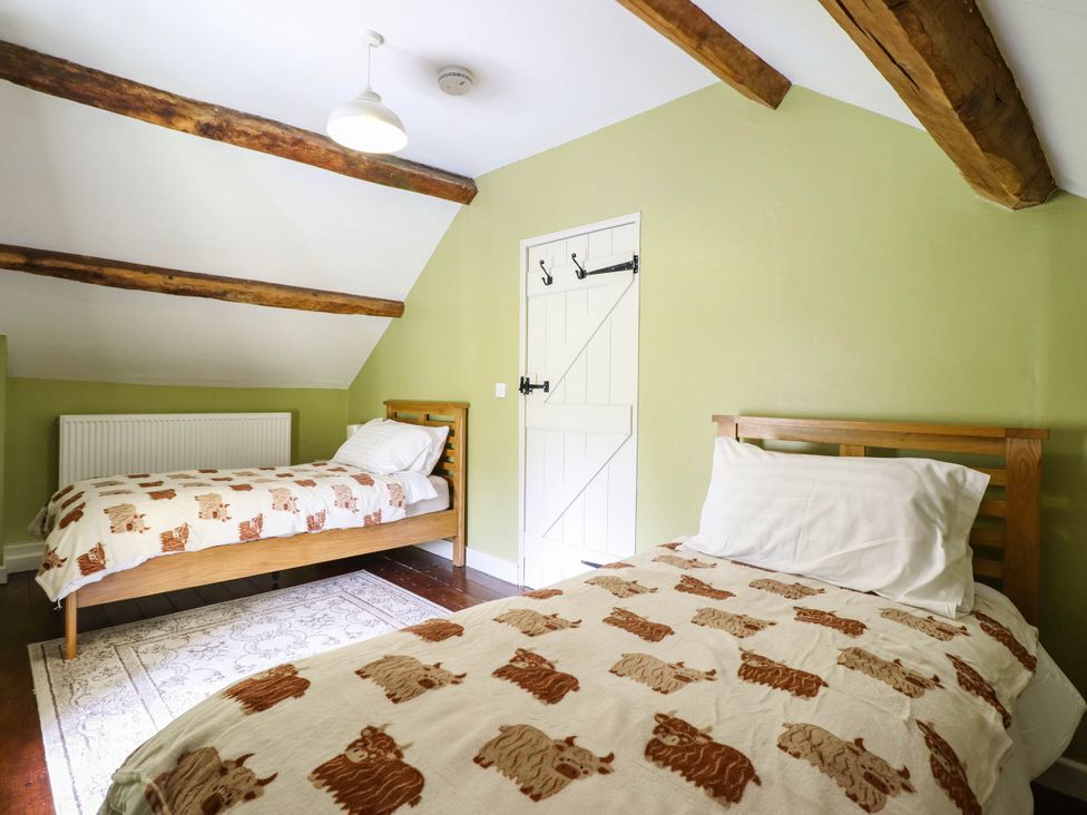 A bedroom with two beds and a door at Frondirion in Dinas Mawddwy