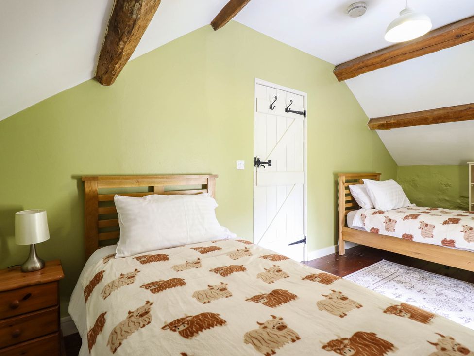A bedroom with two beds and a door at Frondirion in Dinas Mawddwy