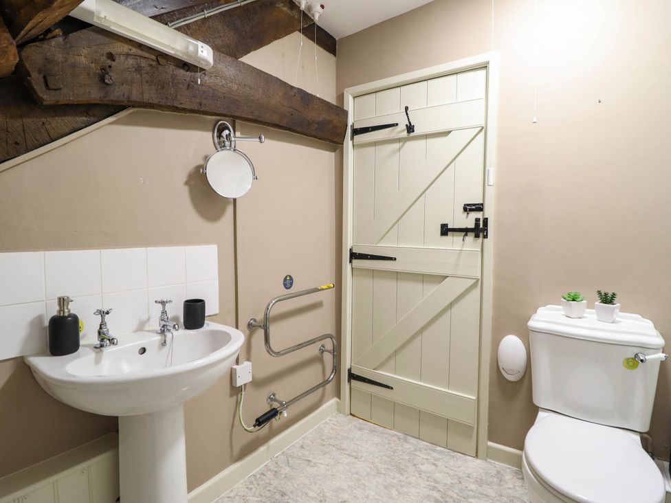 A bathroom with a sink, toilet, and mirror at Frondirion in Dinas Mawddwy