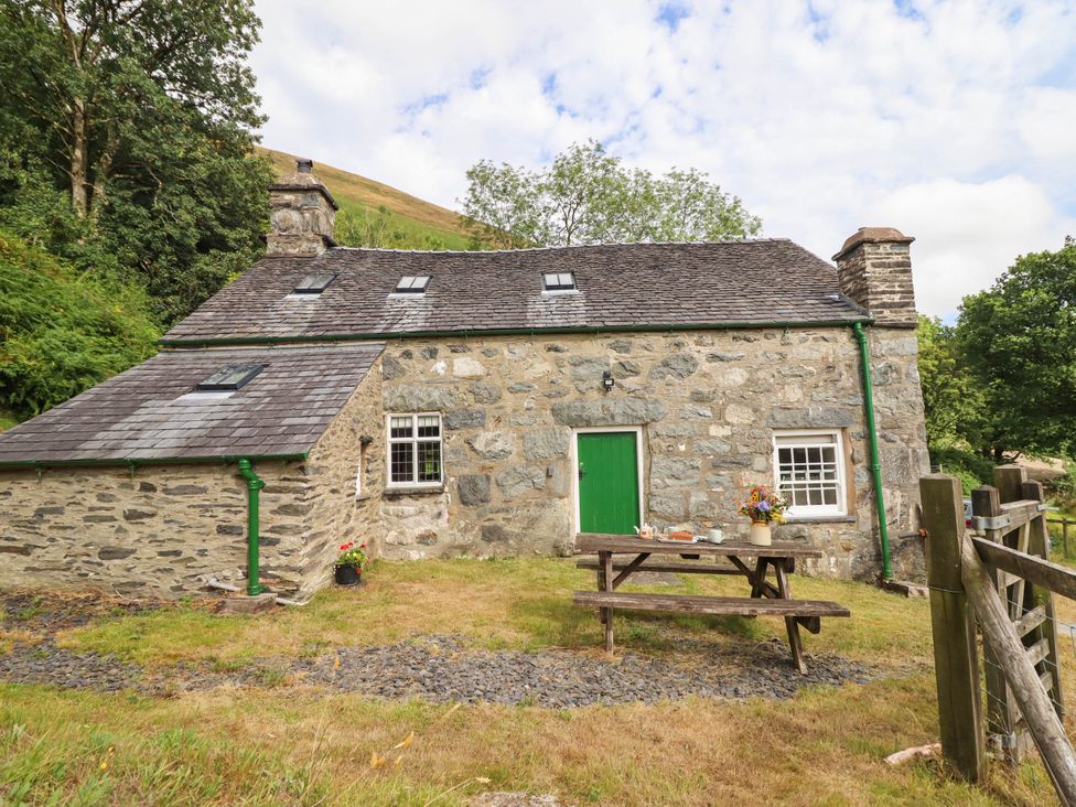 A cottage with a green door and table outside at Frondirion Dinas Mawddwy