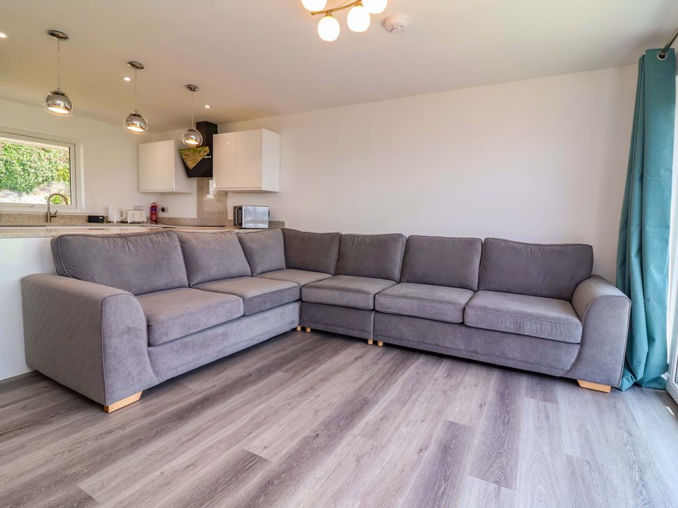 A living room with a gray sofa and kitchen area at 15 Chichester Park