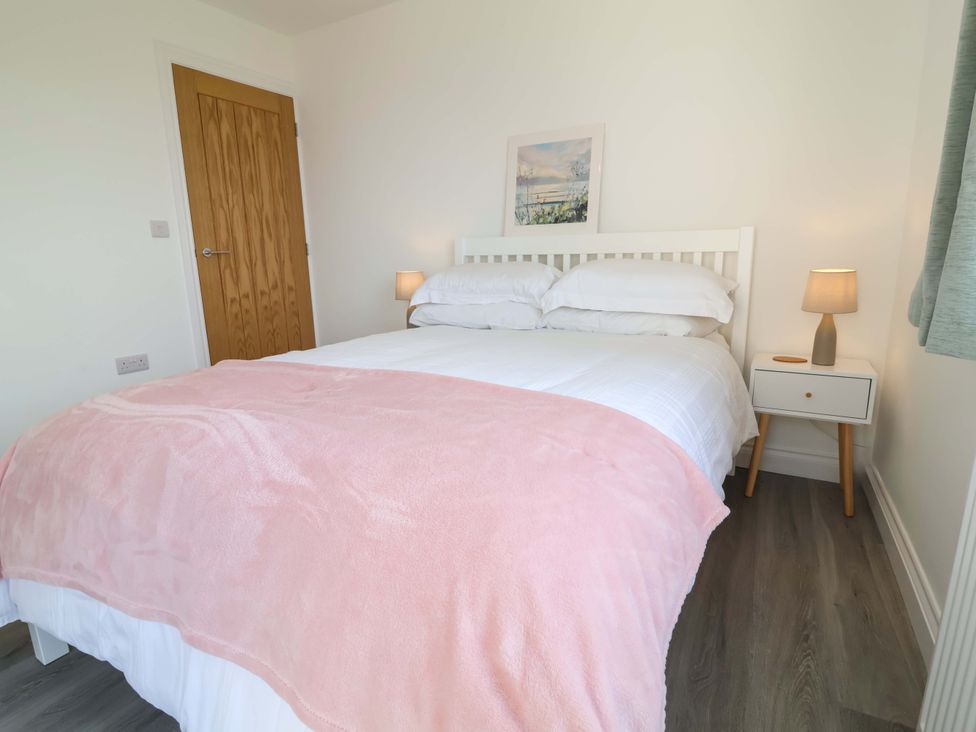 A bedroom with a bed, bedside table, and lamp at 15 Chichester Park