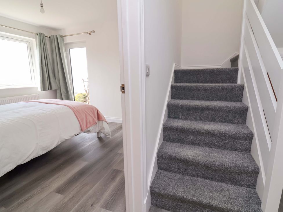 A bedroom with a bed and staircase at 15 Chichester Park