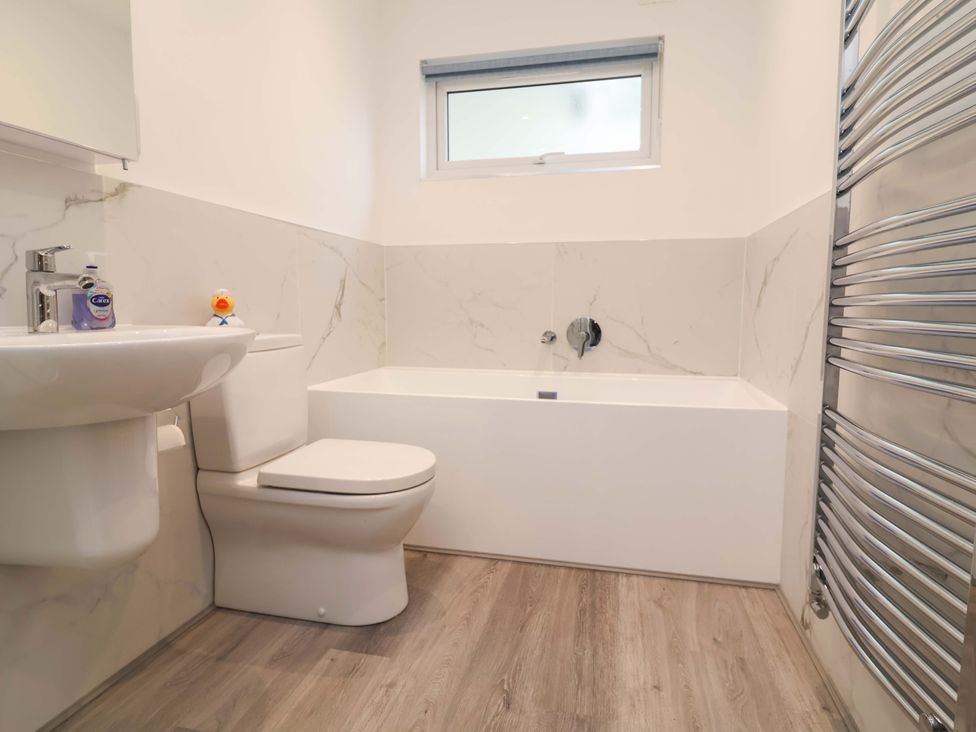 A bathroom with a sink, toilet, bathtub and mirror at Belvedere in Woolacombe
