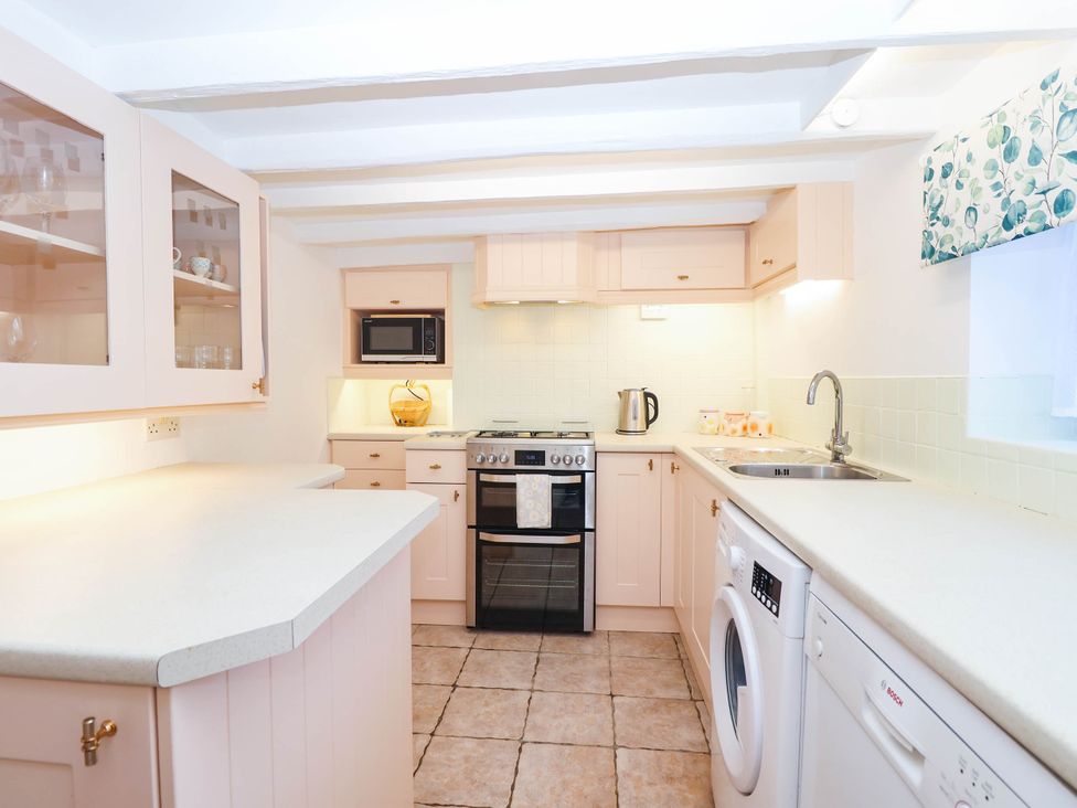 A kitchen with appliances and storage at Swallow Cottage in Sheviock near Crafthole