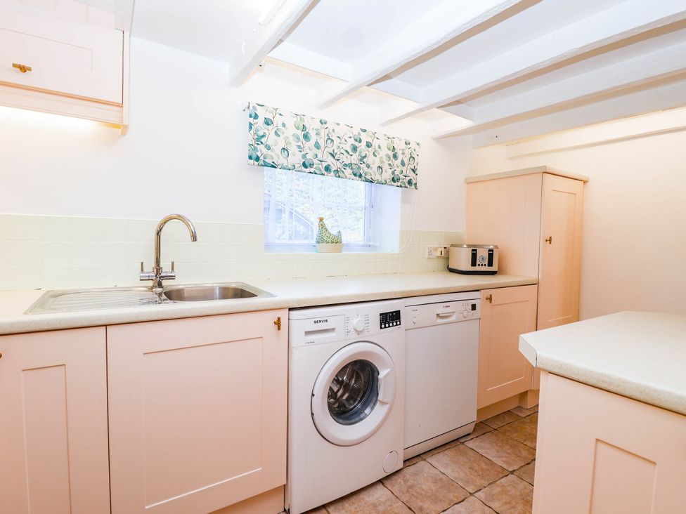 A kitchen with a sink, dishwasher, and washing machine at Swallow Cottage in Sheviock near Crafthole