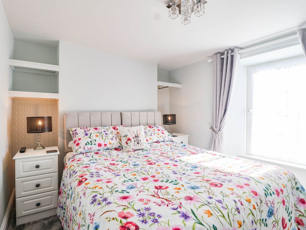 A bedroom with a bed and nightstand at Swallow Cottage in Sheviock near Crafthole