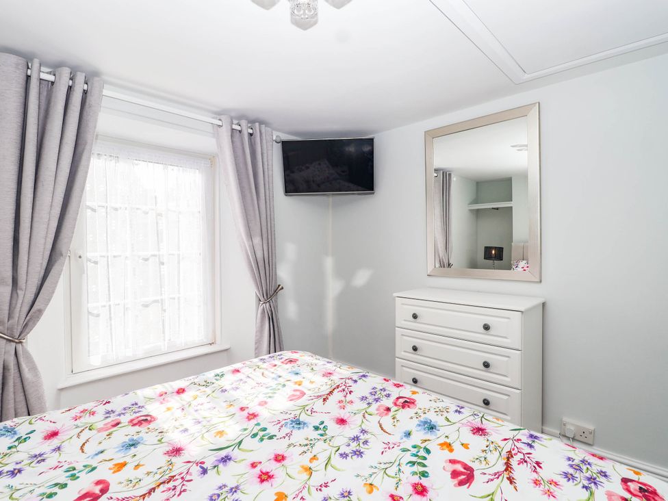 A bedroom with a bed and television at Swallow Cottage in Sheviock near Crafthole