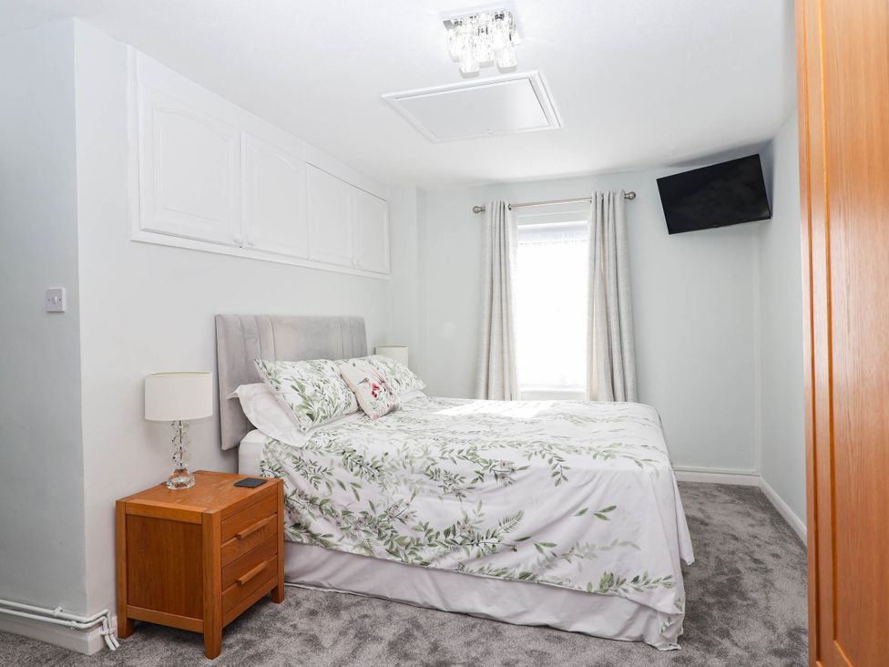 A bedroom with a bed and nightstand at Swallow Cottage in Sheviock near Crafthole
