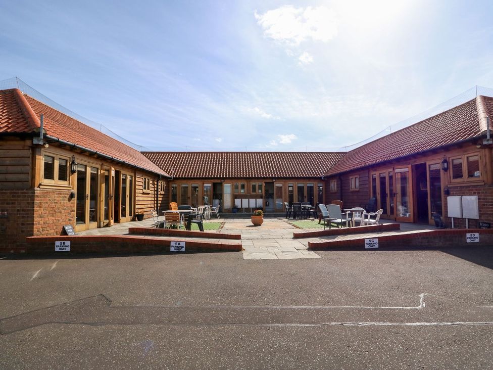 An outdoor area with seating and surrounding buildings at 5b Hideaways in Hunstanton