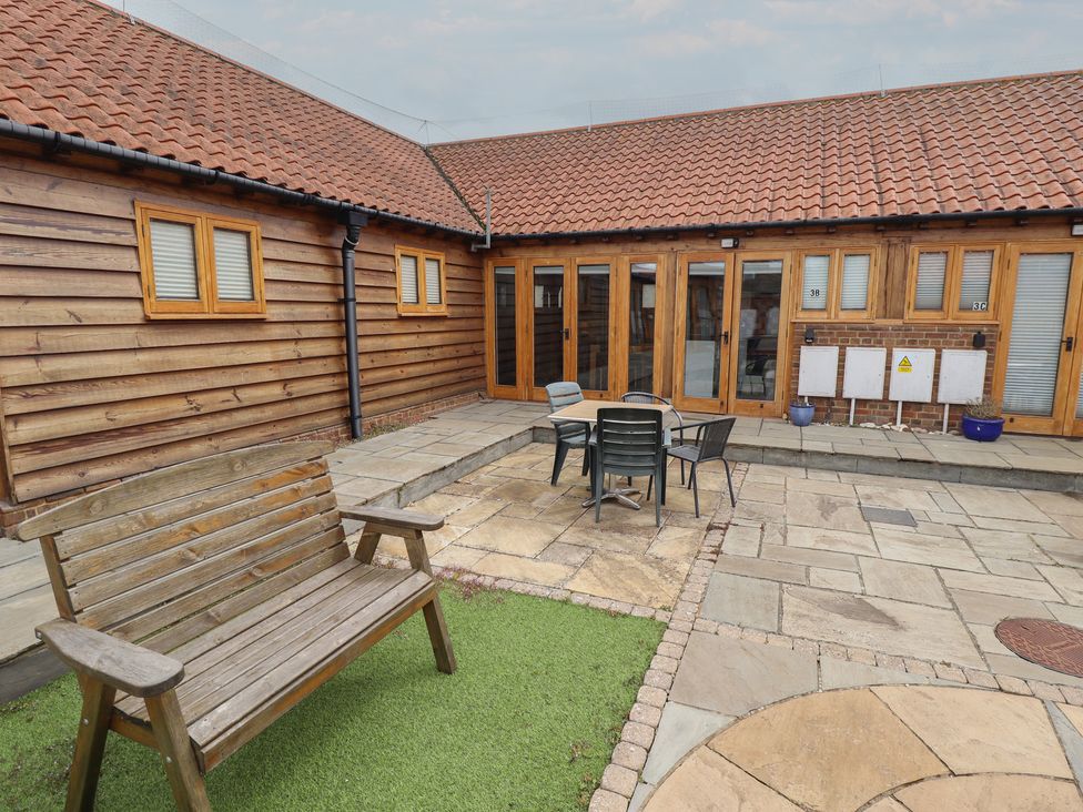 An outdoor garden area with a wooden bench and dining set at 3b Hideaways in Hunstanton