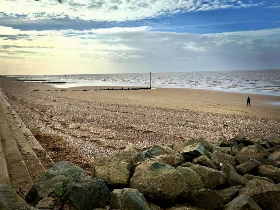 A beach with a person walking at 3b Hideaways in Hunstanton
