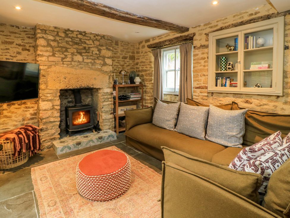 A living room with a fireplace and sofa at Well Cottage in Charlbury