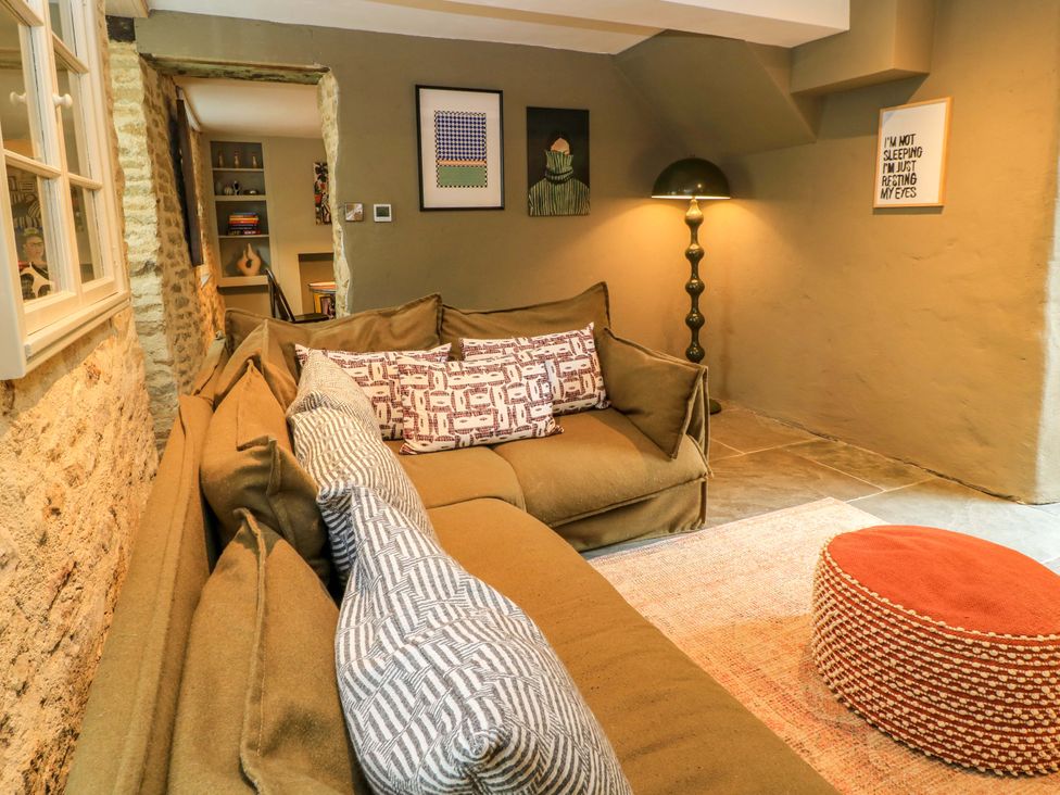A living room with a sofa and lamp at Well Cottage in Charlbury
