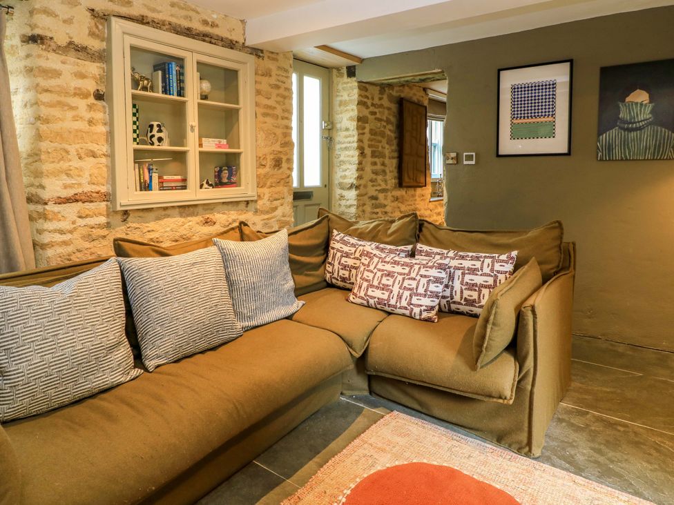 A living room with a sofa and bookshelf at Well Cottage in Charlbury