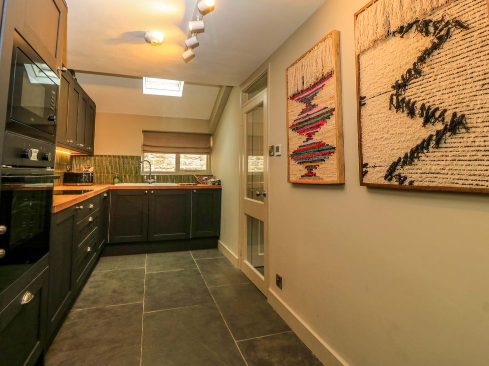 A kitchen with dark cabinets and wall art at Well Cottage in Charlbury
