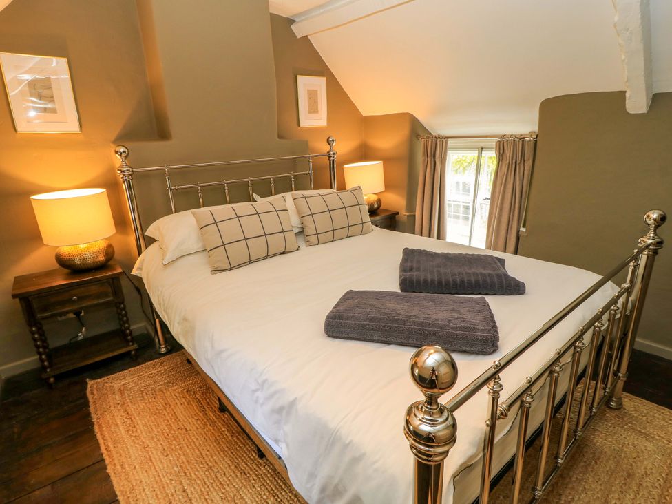 A bedroom with a bed and nightstand at Well Cottage in Charlbury
