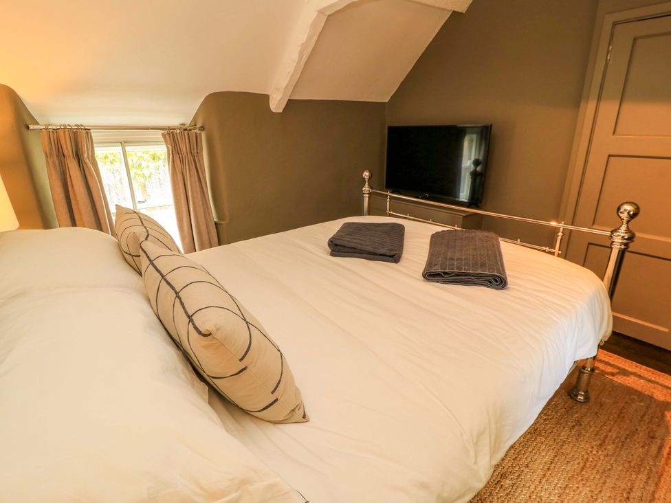 A bedroom with a bed and television at Well Cottage in Charlbury