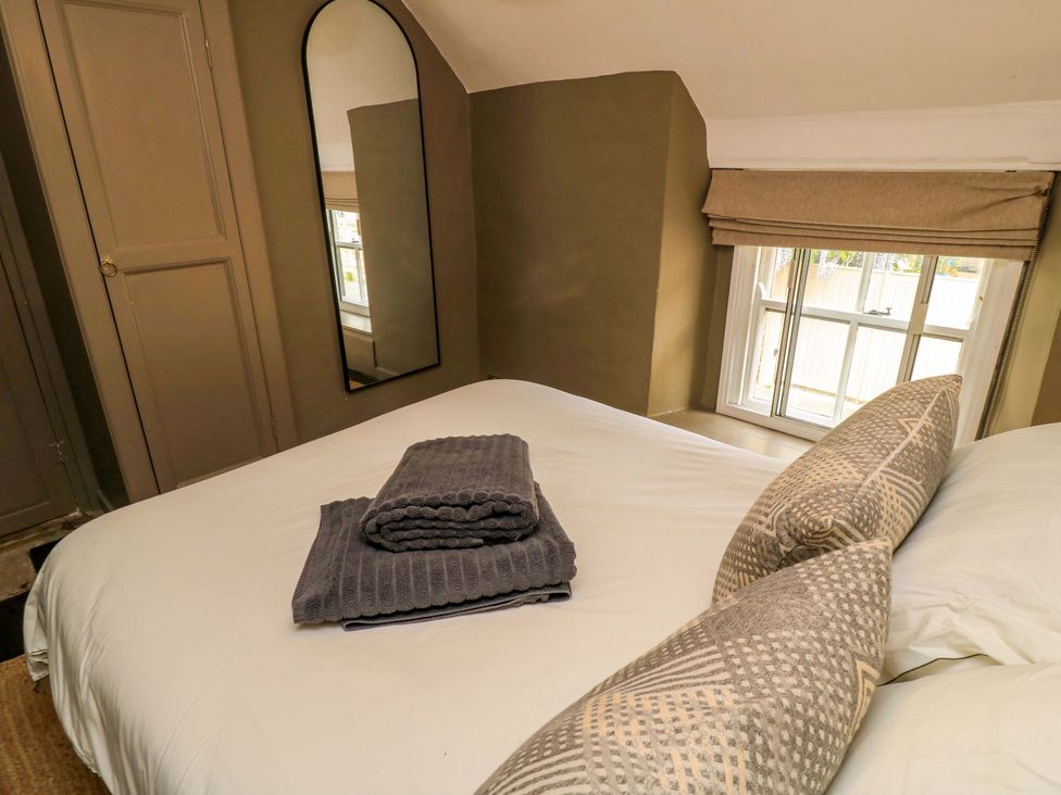 A bedroom with a bed and towels at Well Cottage in Charlbury