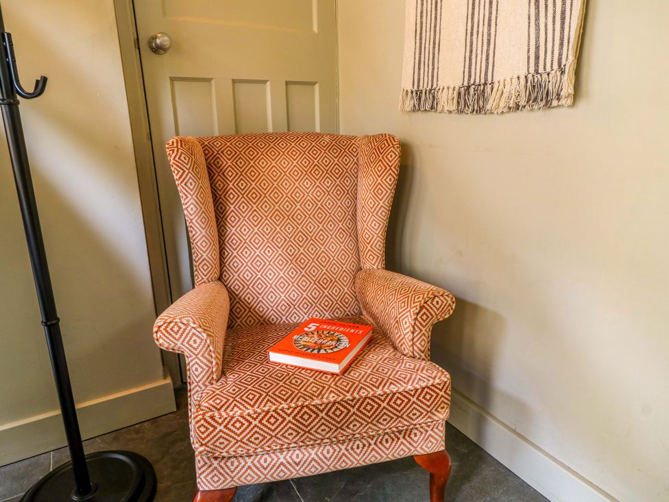 A snug with a chair and a book at Well Cottage in Charlbury