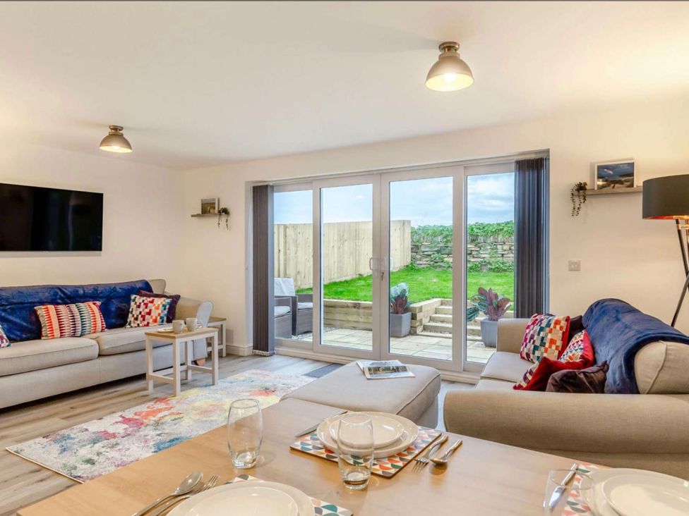 A living room with sofas and a dining table at Buttercup Cottage in Wadebridge