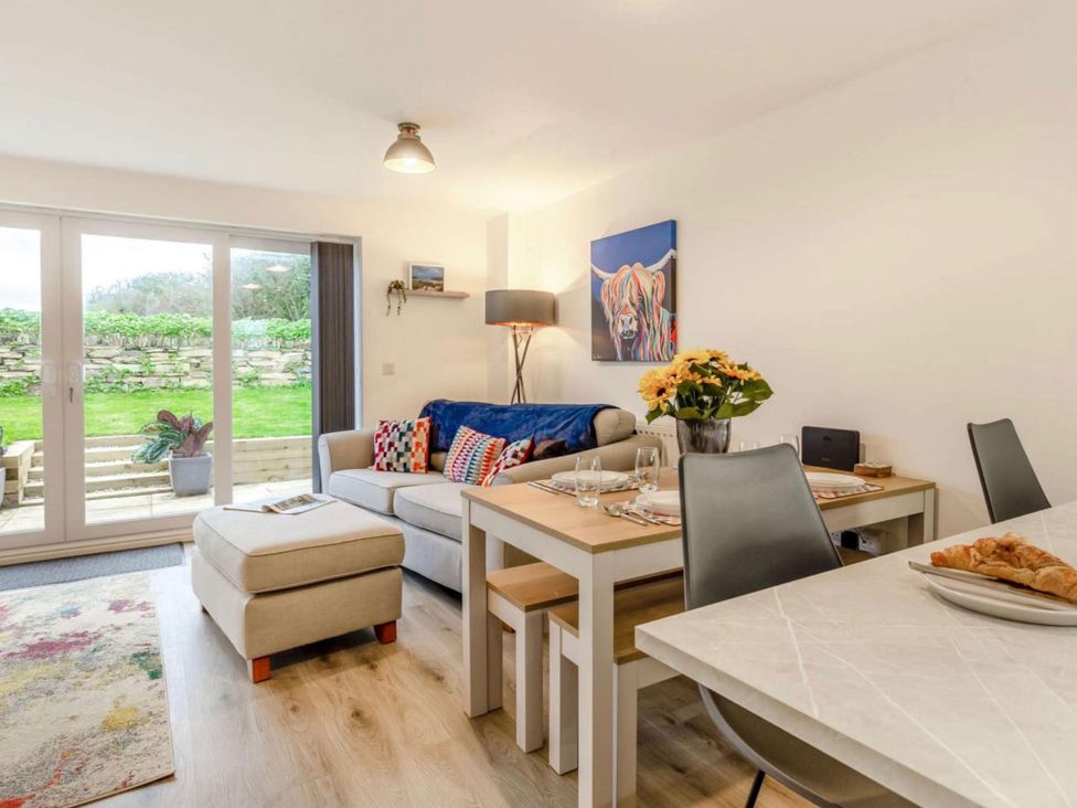 A living room with a sofa and dining table at Buttercup Cottage in Wadebridge
