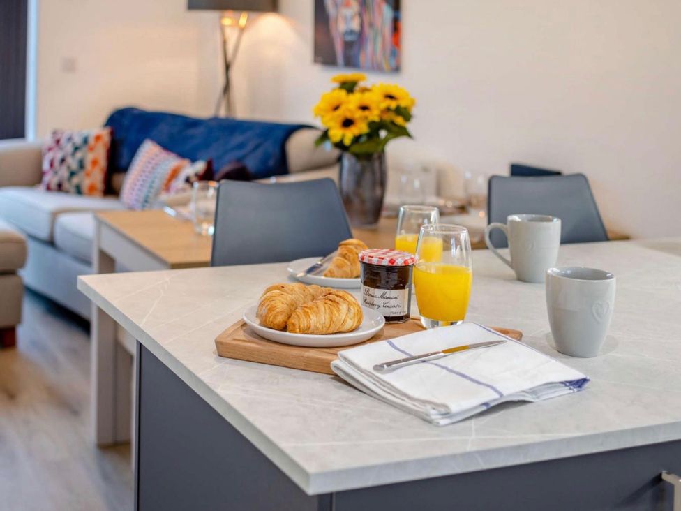 A kitchen with croissants and orange juice on a island at Buttercup Cottage Wadebridge
