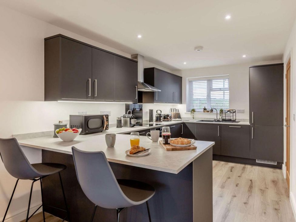 A kitchen with bar stools and a microwave at Buttercup Cottage in Wadebridge