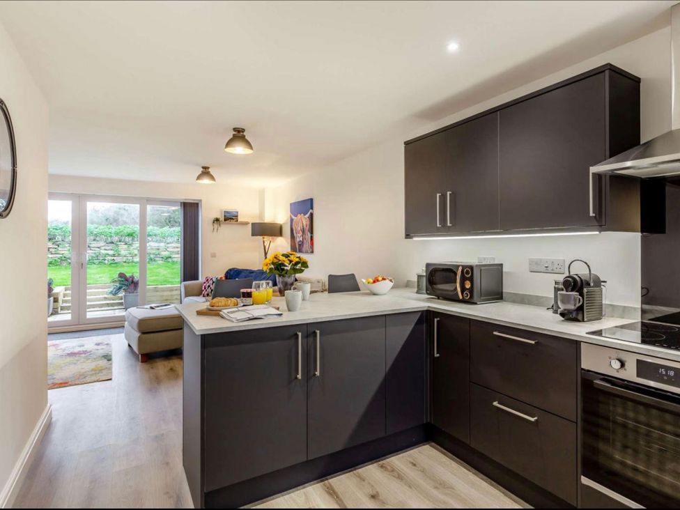A kitchen with modern cabinets and appliances at Buttercup Cottage in Wadebridge