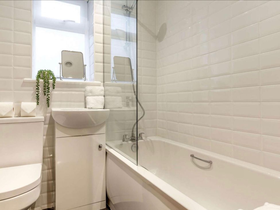 A bathroom with a bathtub, toilet, and sink at Buttercup Cottage in Wadebridge