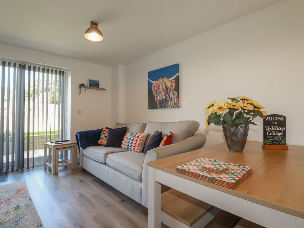 A living room with a sofa and table at Buttercup Cottage in St Merryn