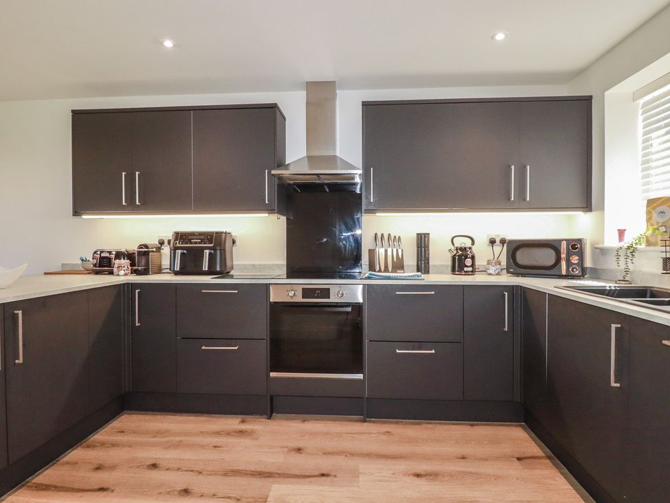 A kitchen with modern appliances and cabinetry at Buttercup Cottage in St Merryn