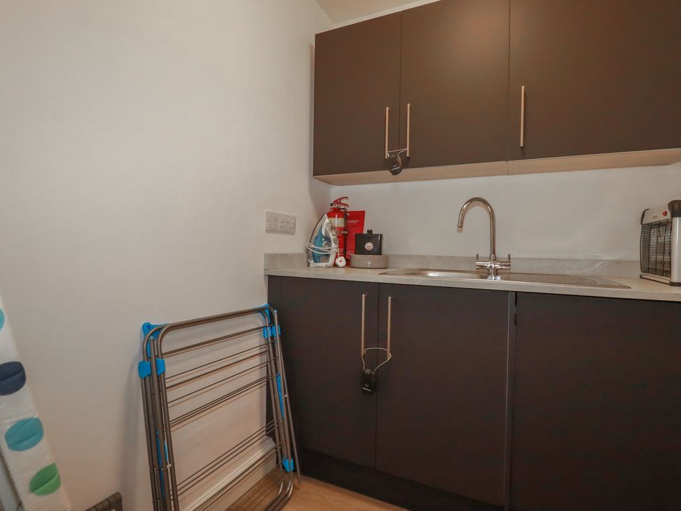 A laundry room with a sink and cabinets at Buttercup Cottage St Merryn
